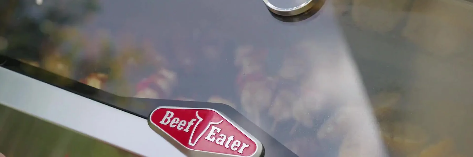 Close view of the red BeefEater badge on the stainless steel hood of a barbecue