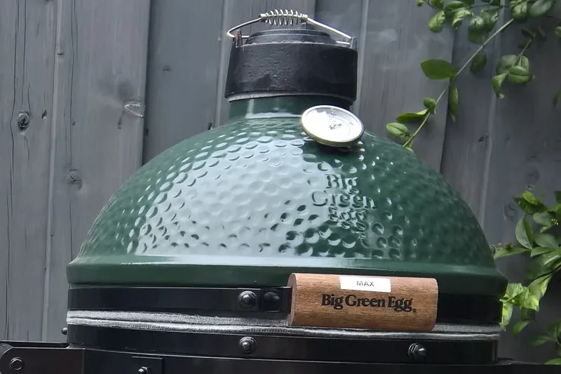 Big Green Egg MiniMax kamado in its carrier on a wooden table outdoors
