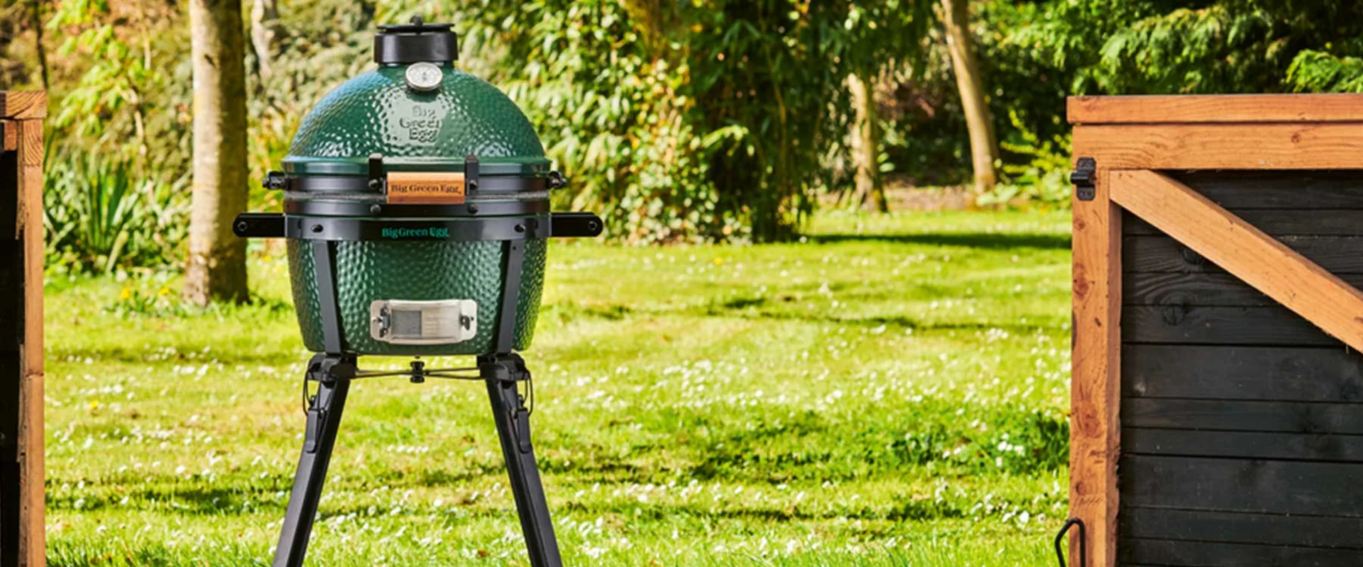 Big Green Egg MiniMax on its carrier stand on a sunny garden lawn