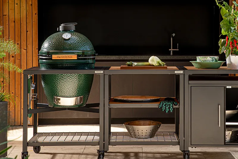Big Green Egg kamado set in a black modular outdoor kitchen with shelves and a cabinet on a terrace