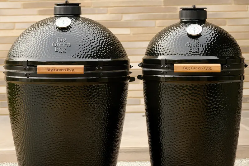 Two black Big Green Egg Onyx Edition kamados of different sizes standing side by side