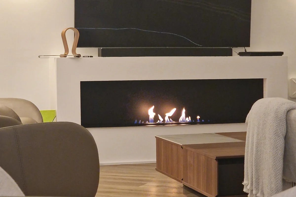 Linear EcoSmart bioethanol burner set into a white built-in fireplace wall in a modern living room