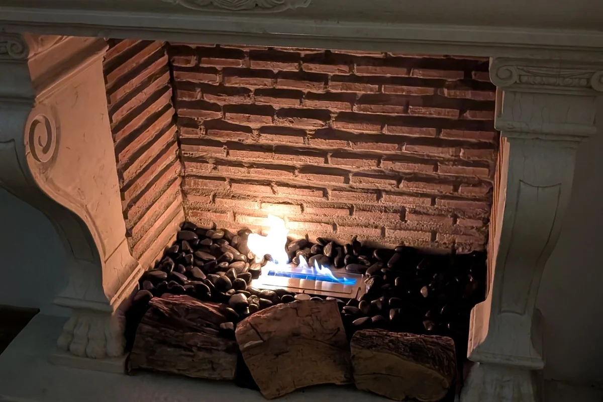EcoSmart XS340 bioethanol burner among stones and logs in a classic carved-stone fireplace in a villa in El Madroñal, Marbella
