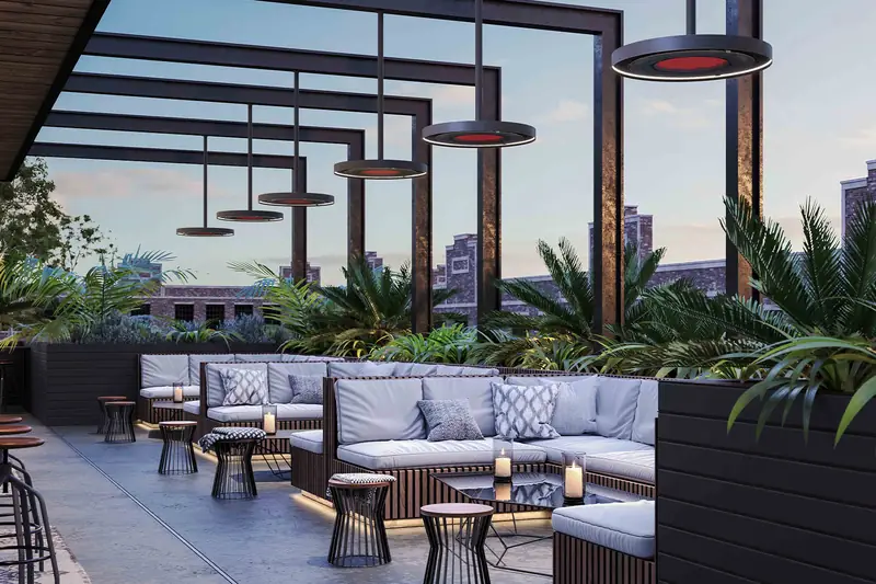 Row of Bromic Eclipse pendant heaters glowing red beneath a black steel pergola over a rooftop lounge at dusk