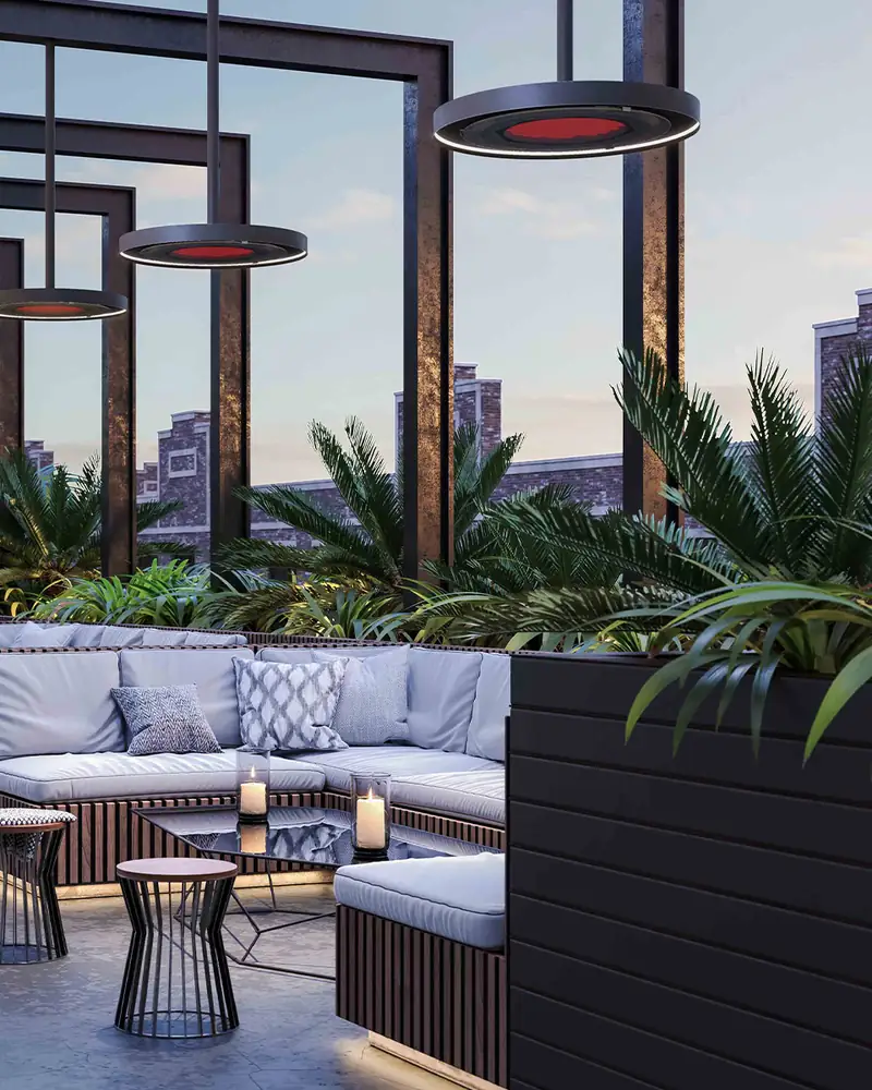 Row of Bromic Eclipse pendant heaters glowing red beneath a black steel pergola over a rooftop lounge at dusk