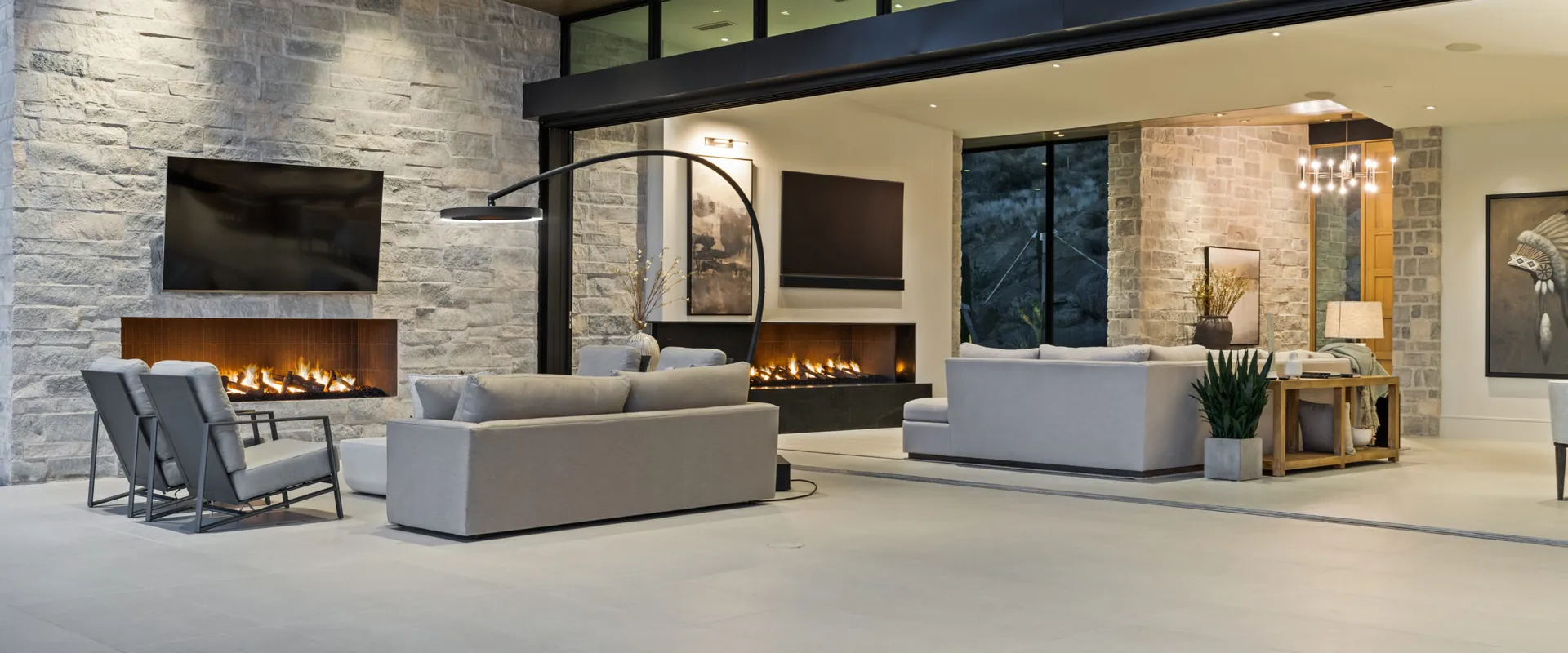 Bromic Eclipse Smart-Heat Portable heater arching over a sofa on the open terrace of a modern home, with a stone wall and a linear fireplace behind
