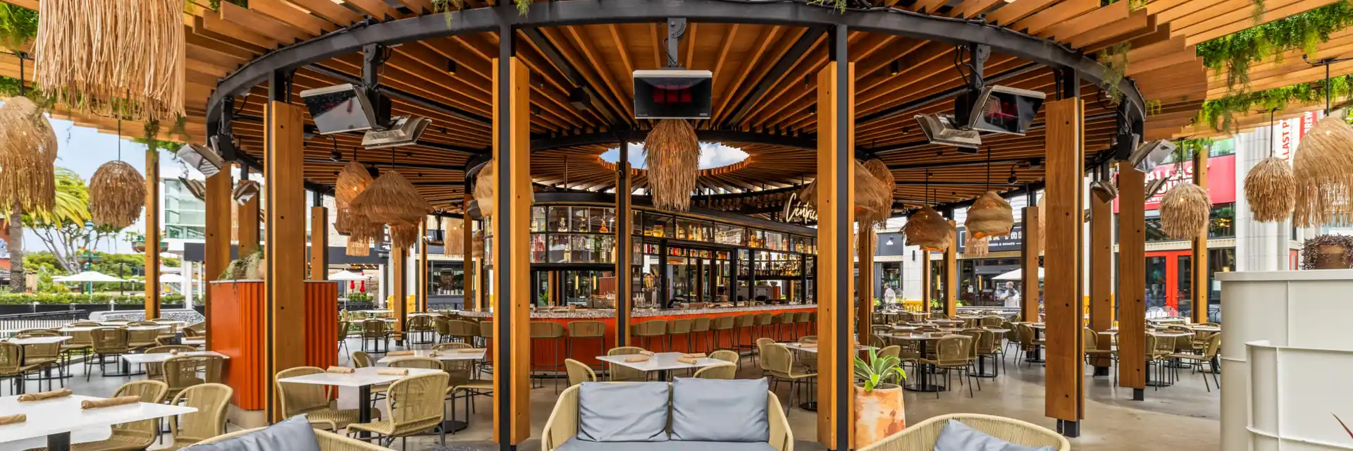 Bromic heaters under the timber pergola of a restaurant terrace, over a lounge with wicker lamps