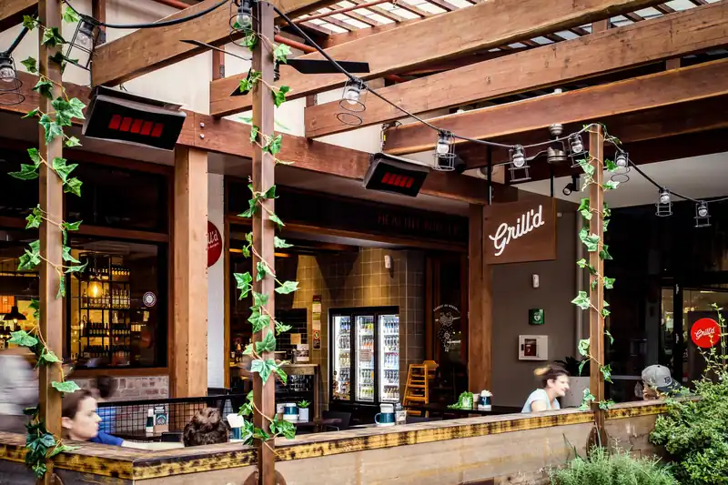 Bromic heaters under the timber pergola of a restaurant terrace with climbing plants