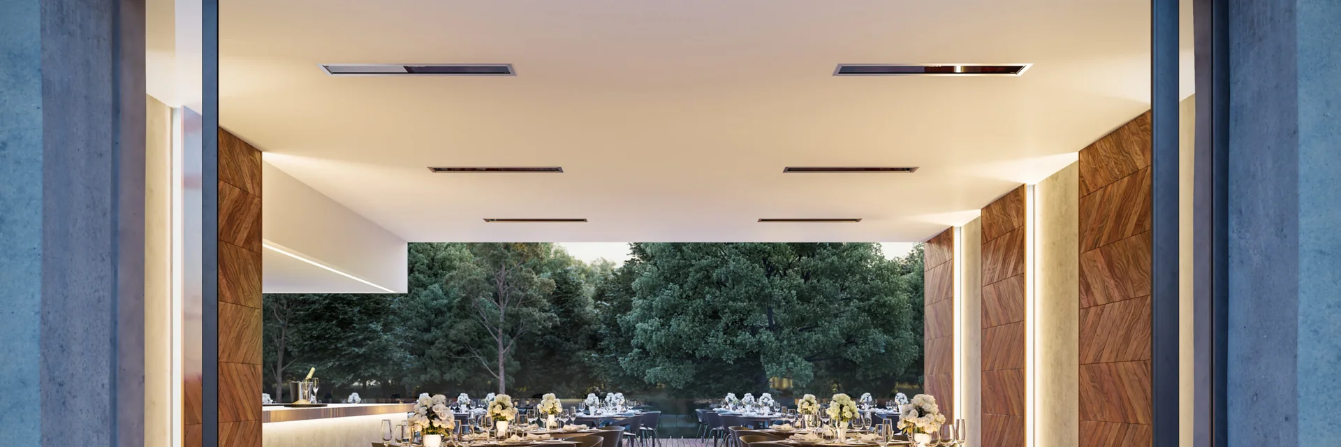 Black Bromic Platinum Electric heaters recessed in the white ceiling of a restaurant terrace with set tables, opening onto trees
