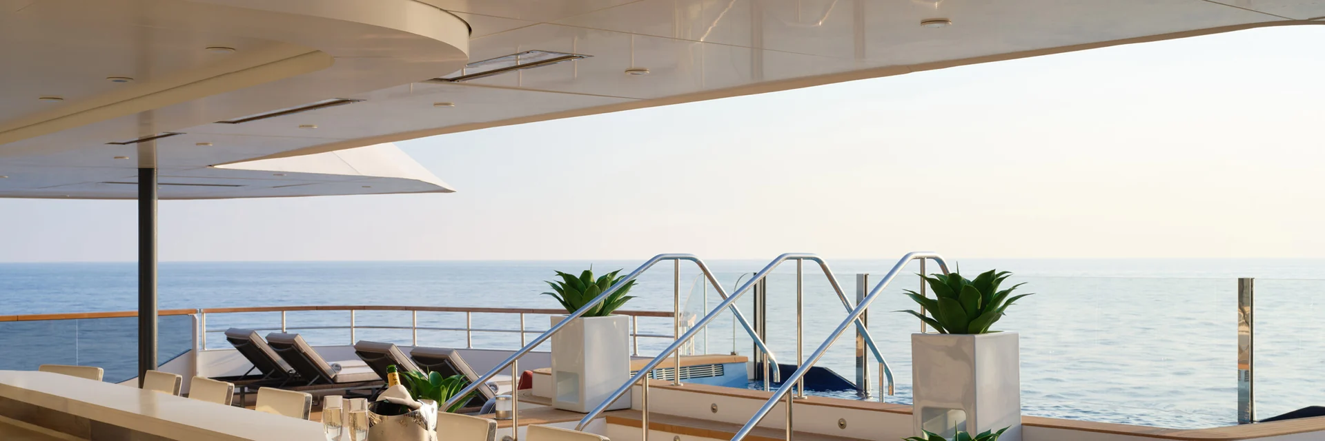 Bromic Platinum Electric marine heaters set flush in the ceiling above a deck bar with cream stools, sun loungers and the open sea beyond