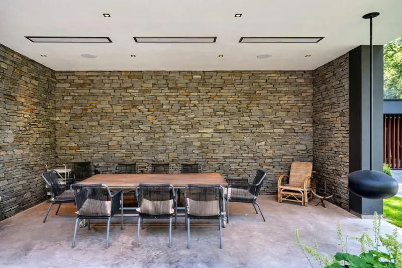Three white Bromic Platinum Electric heaters flush-mounted in the white ceiling of a covered terrace with a dry-stone wall