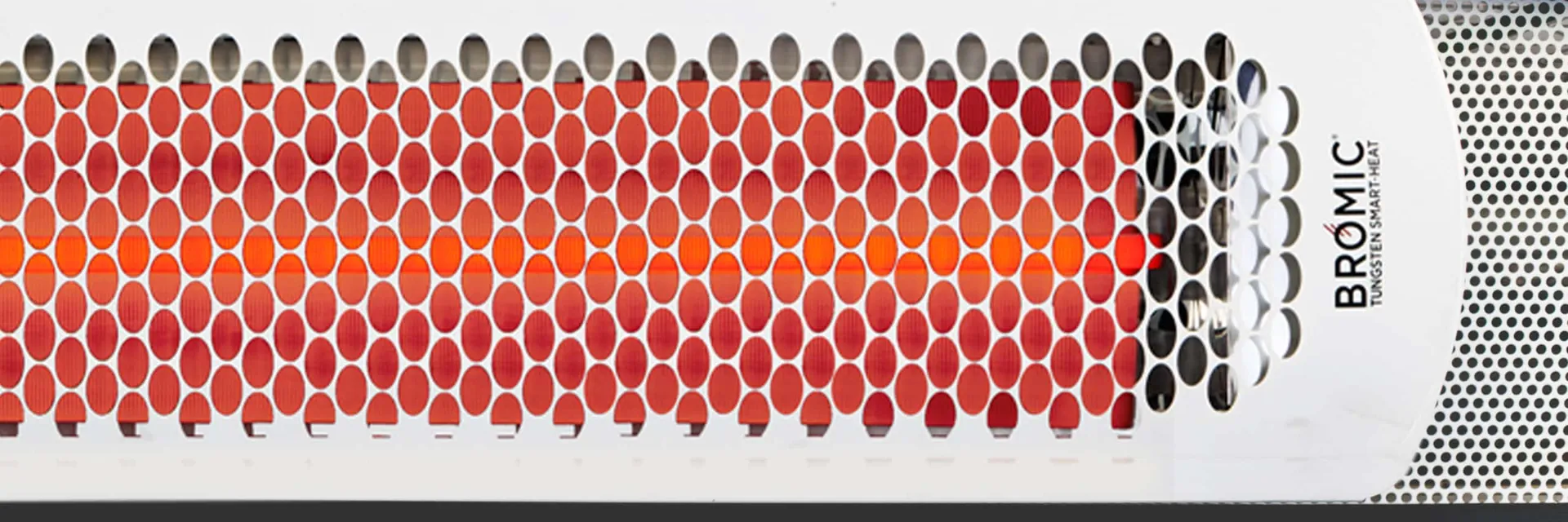 Close-up of a white Bromic Tungsten Smart-Heat electric heater with its element glowing red behind the perforated grille
