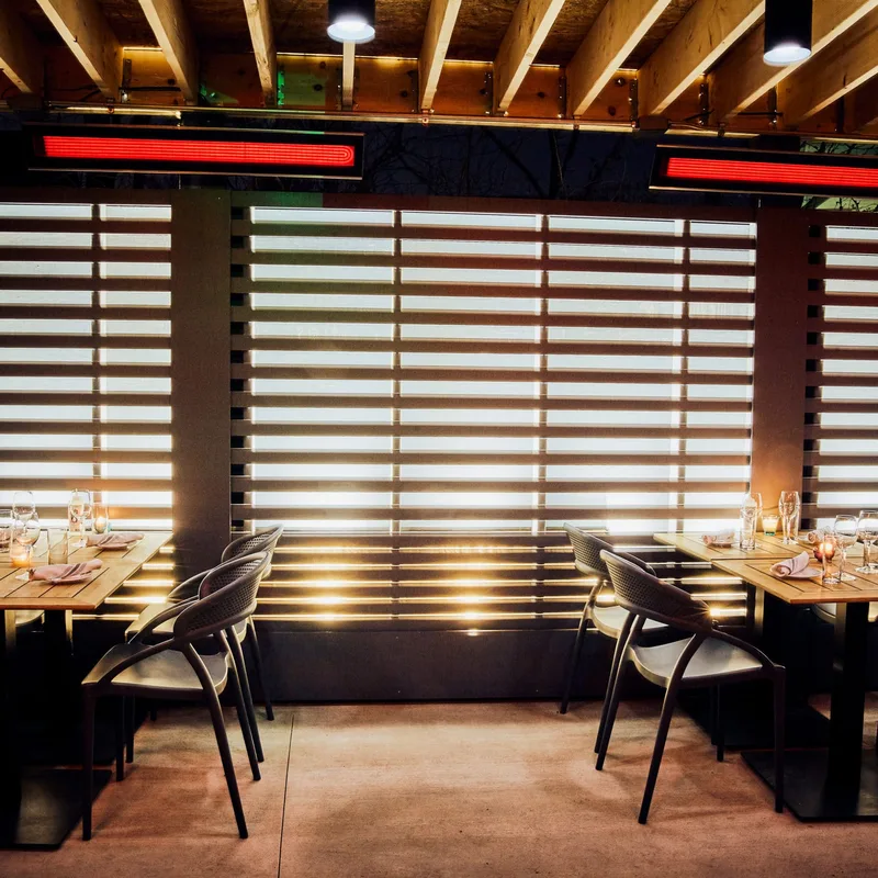 Bromic Tungsten Electric heaters glowing above restaurant tables beneath a slatted timber ceiling