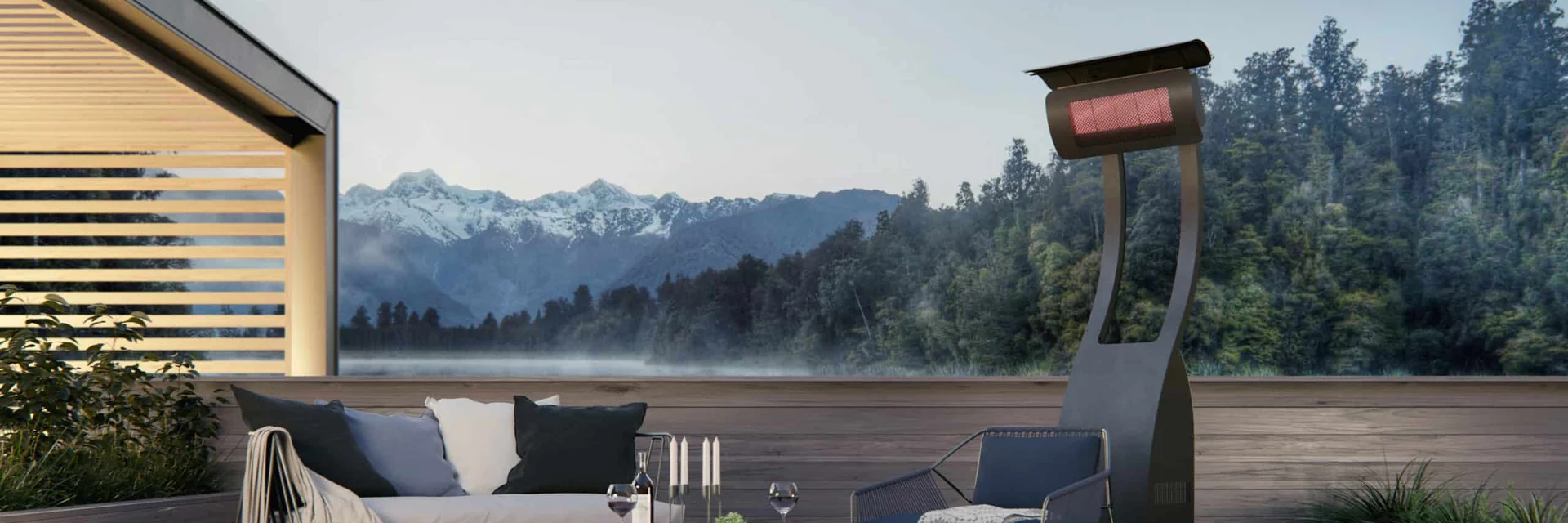 Bromic Tungsten Portable gas heater glowing beside an outdoor sofa on a wooden deck, with a misty forest and distant snowy peaks beyond