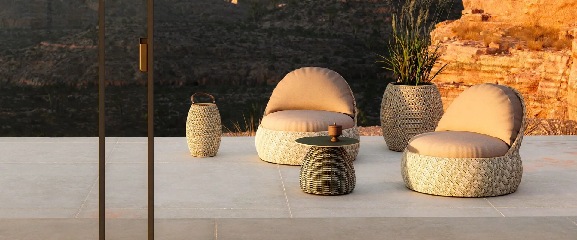 Two Dedon Dala lounge chairs with a side table and planter on a terrace, red cliffs glowing behind