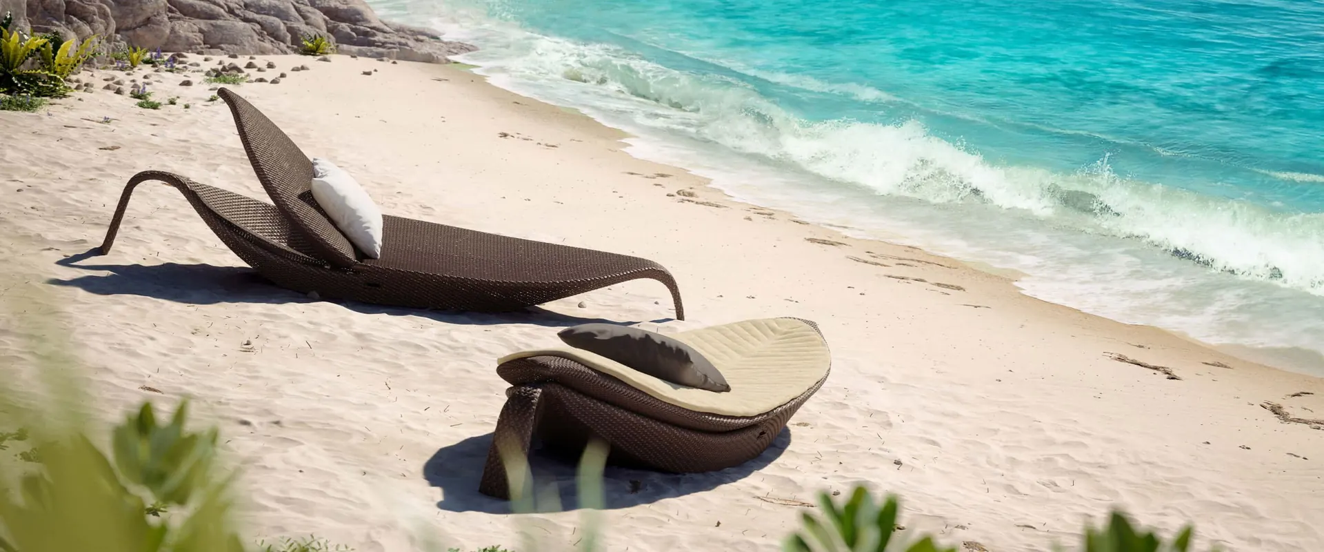 Two Dedon Leaf loungers on the white sand of a curved beach beside turquoise water