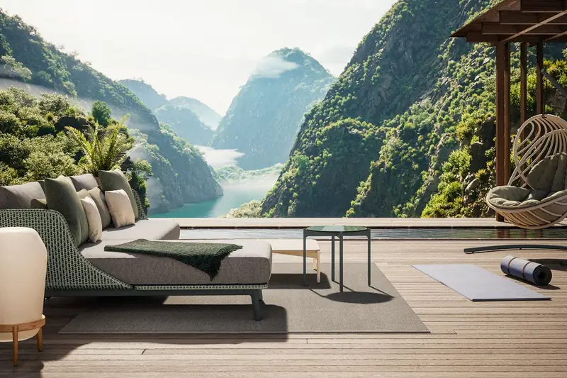 Dedon Mbarq sofa and a Kida hanging lounge chair on a timber terrace overlooking a lake between green mountains