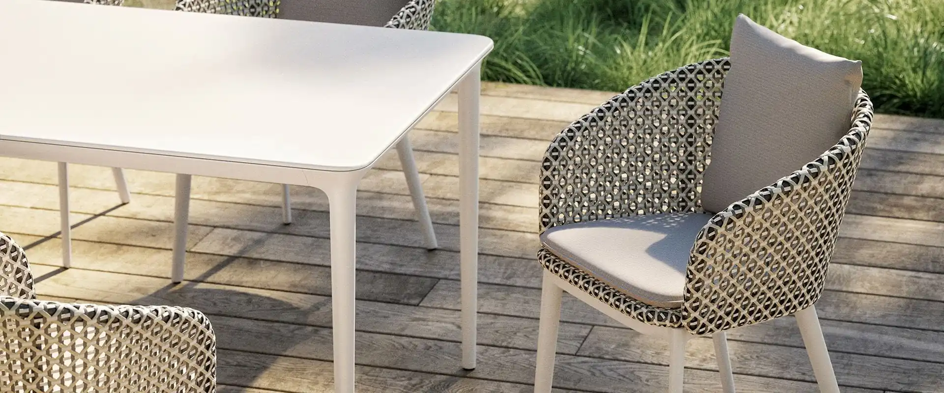 Dedon Mbrace Alu woven dining chairs with slim aluminum legs at a white table on a wooden deck