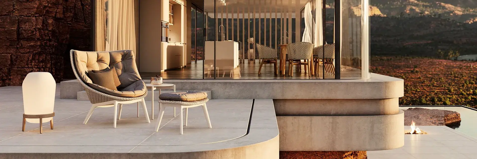 Dedon Mbrace Alu lounge chair, footstool and a lantern on the terrace of a modern house in a rocky desert at sunset