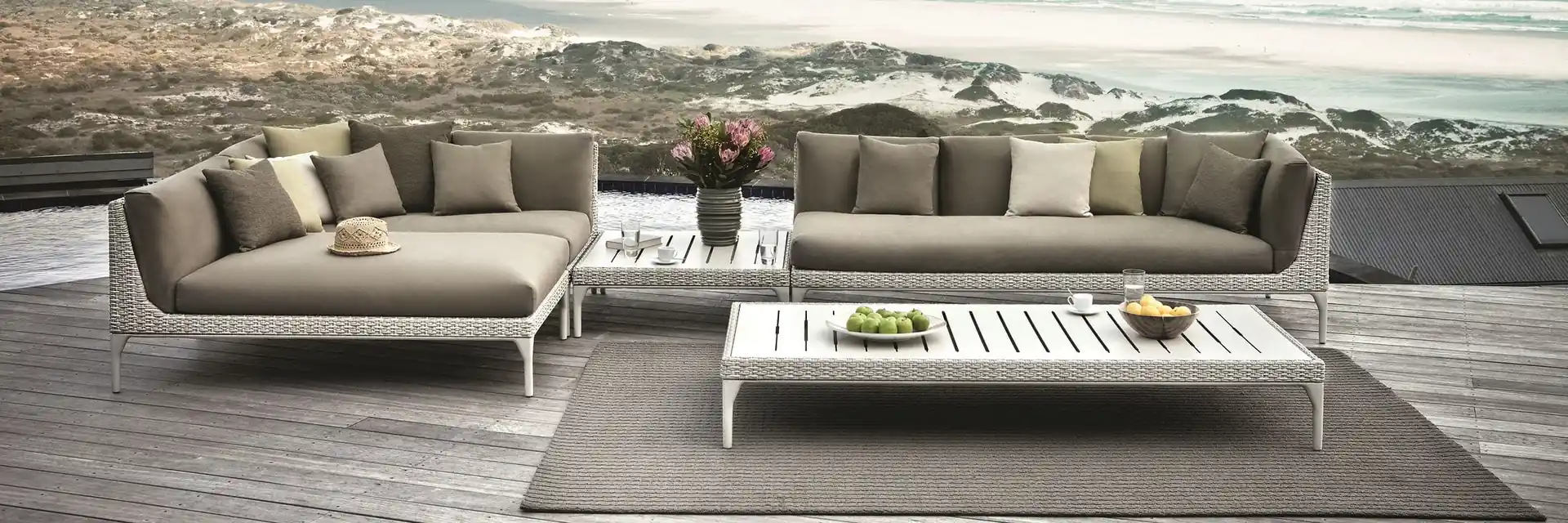Dedon Mu sofa and coffee table on a deck among dunes, overlooking a long beach and the ocean