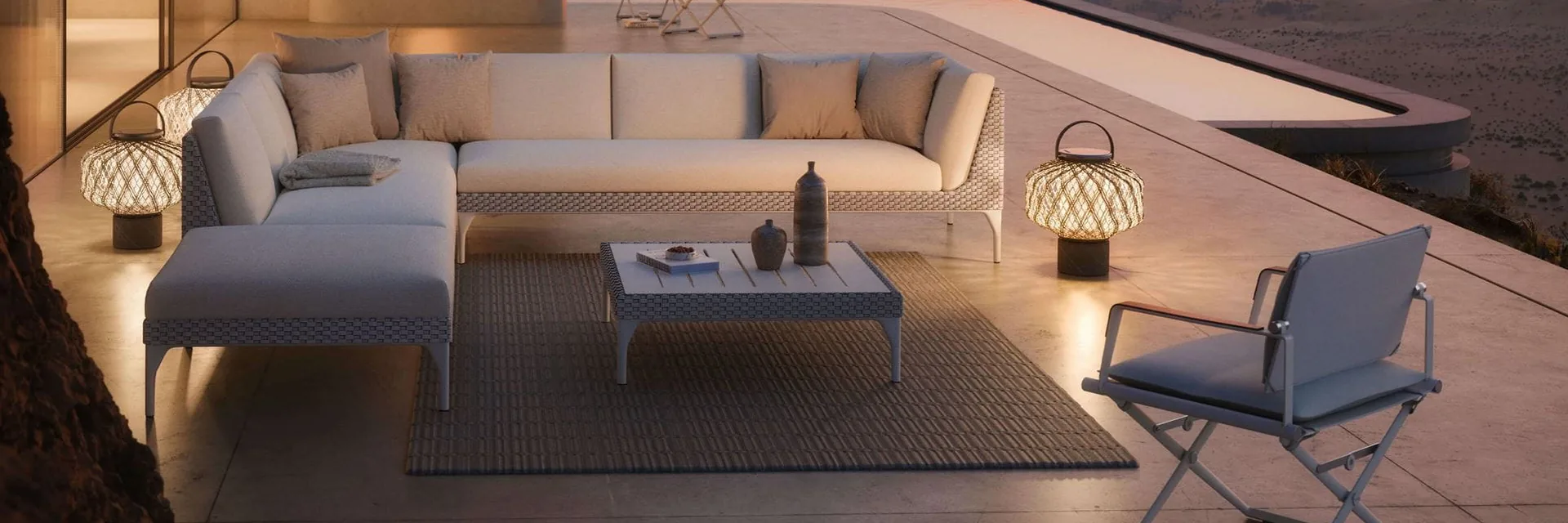 Dedon Mu corner sofa with lanterns and a director's chair on a terrace at dusk, mountains in the distance