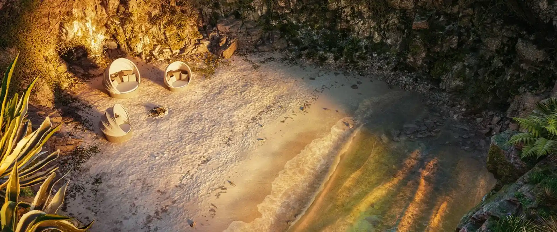 Three Dedon Orbit round loungers on the sand of a small cove, seen from above in evening light