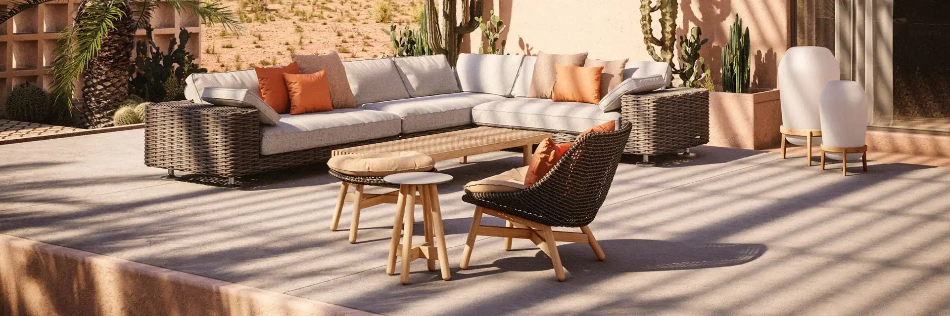 Dedon Paros sofa and lounge chairs on a sunlit terrace with cacti, in front of a pale villa and mountains