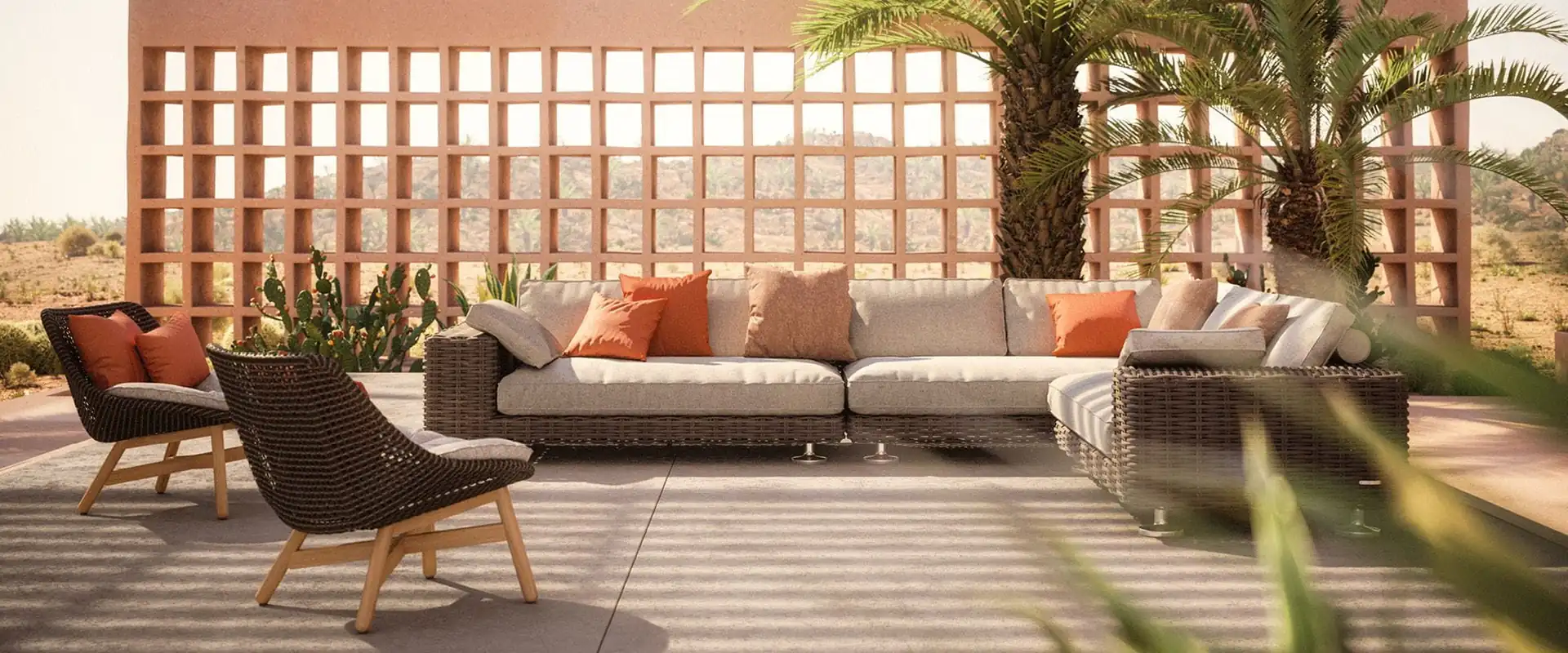 Dedon Paros sofa with orange cushions and two lounge chairs before a terracotta lattice wall and palm trees