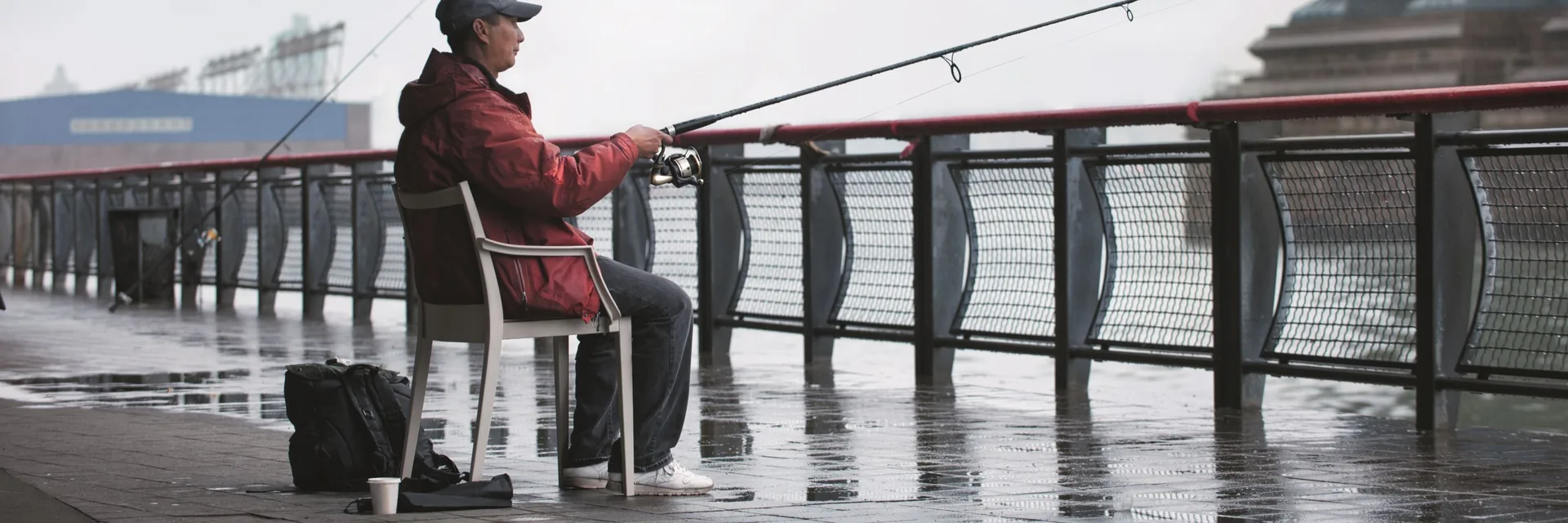 Man fishing from a Dedon Play chair on a wet wooden pier