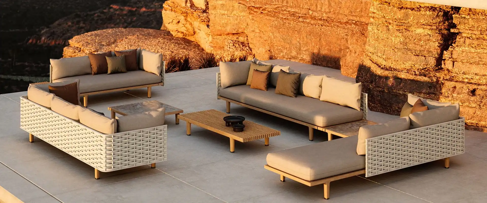 Dedon Sealine sofas and daybed with a teak coffee table on a stone terrace under sunlit cliffs