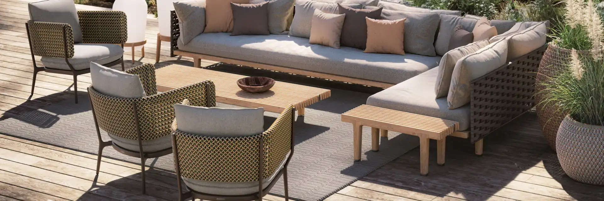 Dedon Sealine corner sofa, armchairs and teak coffee tables on a timber deck surrounded by wild planting