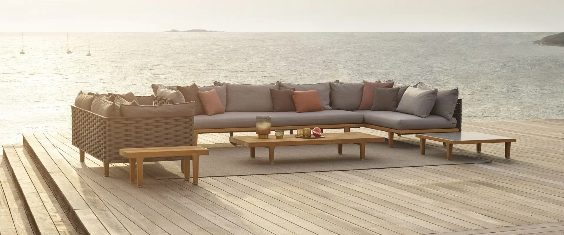 Dedon Sealine sectional sofa and teak coffee tables on a wooden deck overlooking a calm sea