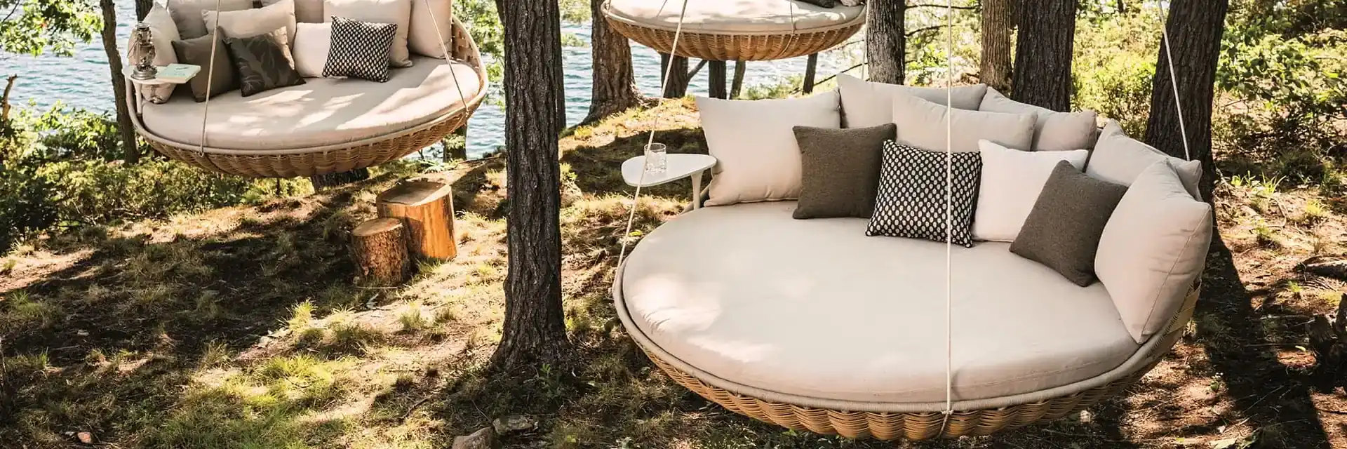 Two Dedon Swingrest hanging loungers with pale cushions suspended among pine trees