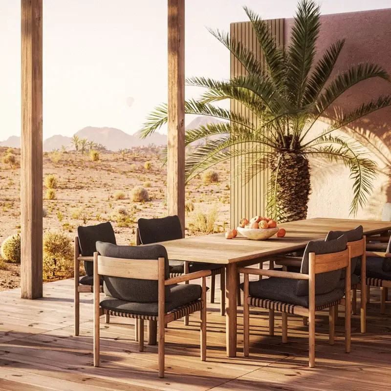 Dedon Tibbo teak dining table and chairs with dark cushions on a covered terrace, a palm and desert behind
