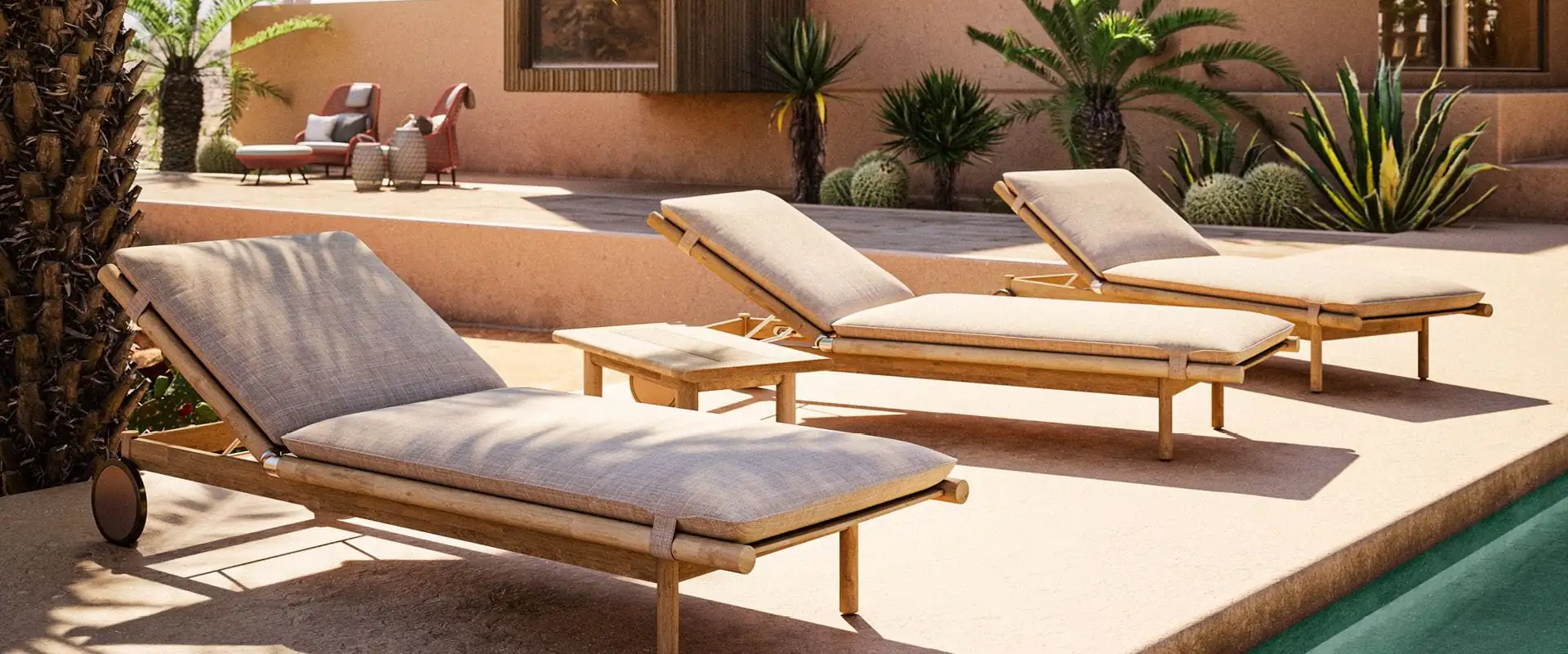 Three Dedon Tibbo teak sun loungers with beige cushions on a terrace beside a pool, palms and agaves behind