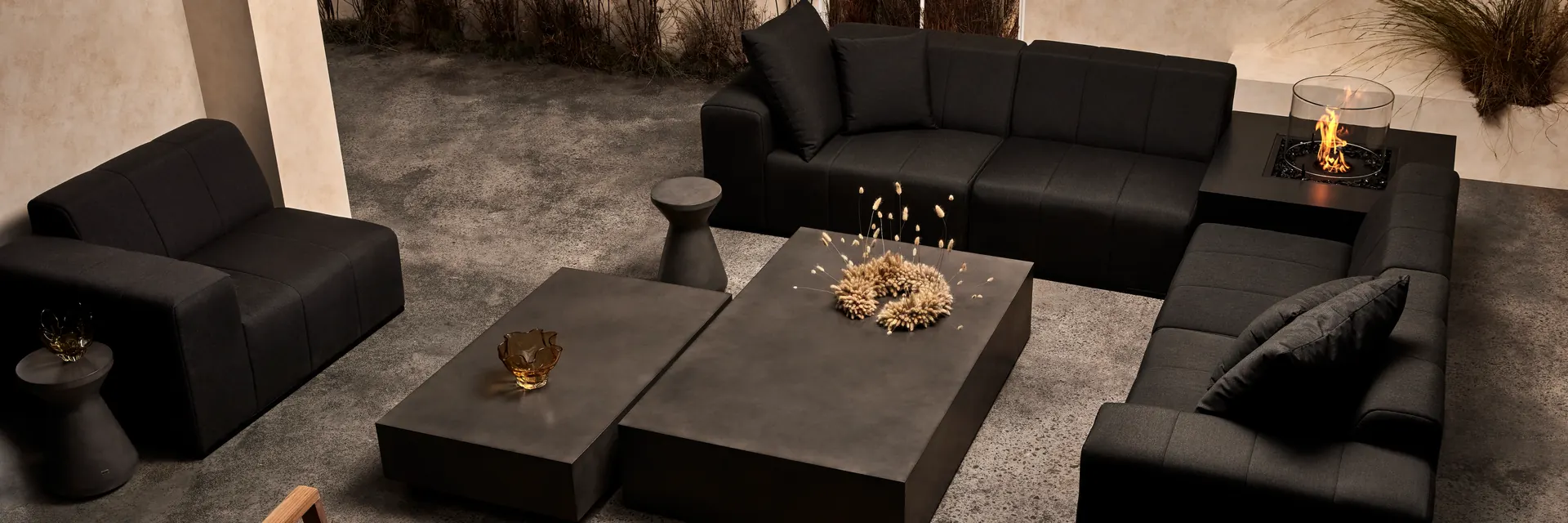 EcoSmart Chaser 38 fire table with a glass screen burning beside black modular sofas and low concrete tables