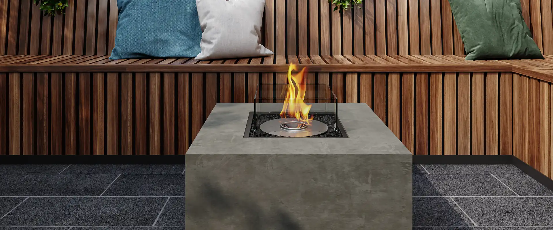 EcoSmart Chaser 38 fire table in concrete burning on dark paving in front of a timber bench with cushions and tropical plants
