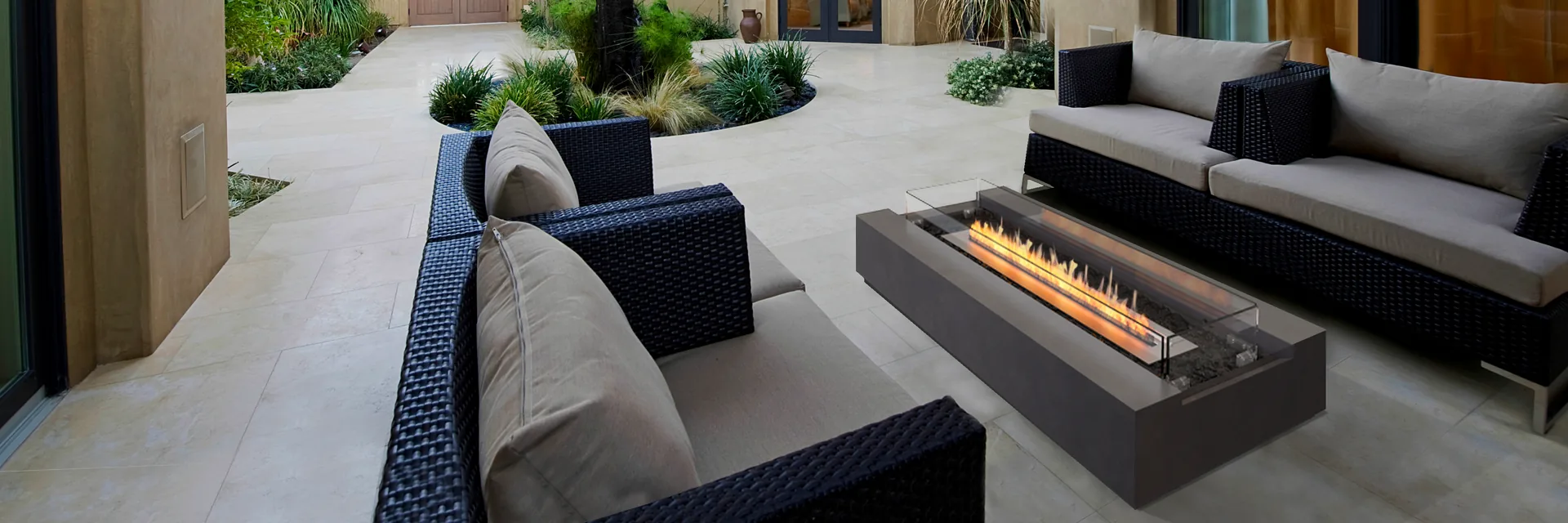 EcoSmart Cosmo 50 fire table with a long line of flame between dark sofas in the courtyard of a Mediterranean-style villa