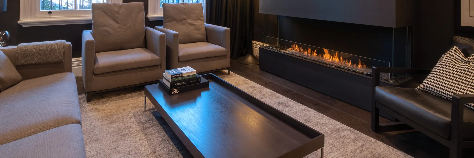 EcoSmart Fire Flex bay fireplace burning below a television in a dark paneled living room with armchairs and arched windows