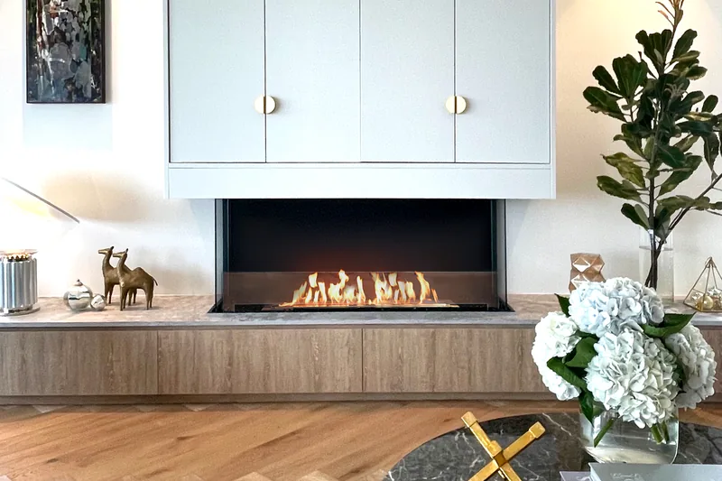 EcoSmart Fire Flex bay fireplace burning below white cabinets in a room with a herringbone floor