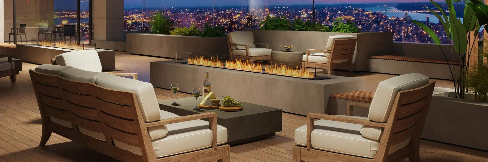 EcoSmart Fire Flex bench fireplace with a long line of flame on a terrace with teak armchairs, overlooking a city at dusk