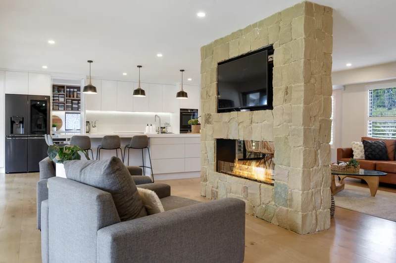 EcoSmart Fire Flex double-sided fireplace burning in a stone-clad divider between a living room and a kitchen