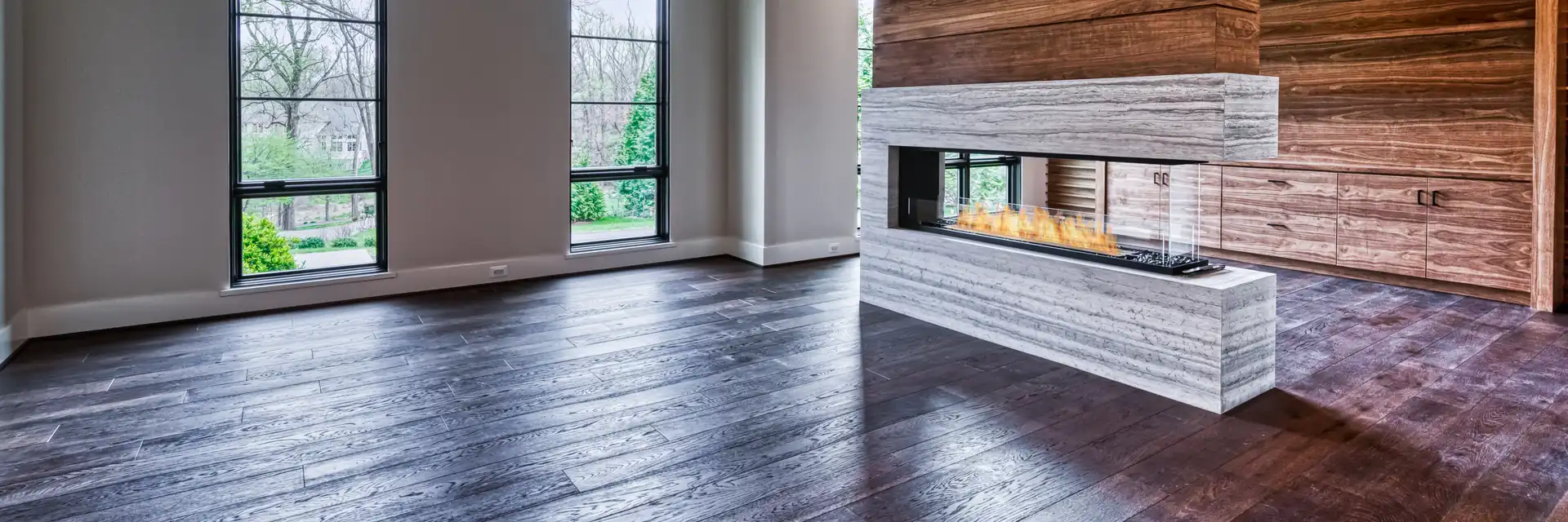 EcoSmart Fire Flex peninsula fireplace burning in a wall of pale stone and reclaimed timber in a tall living room