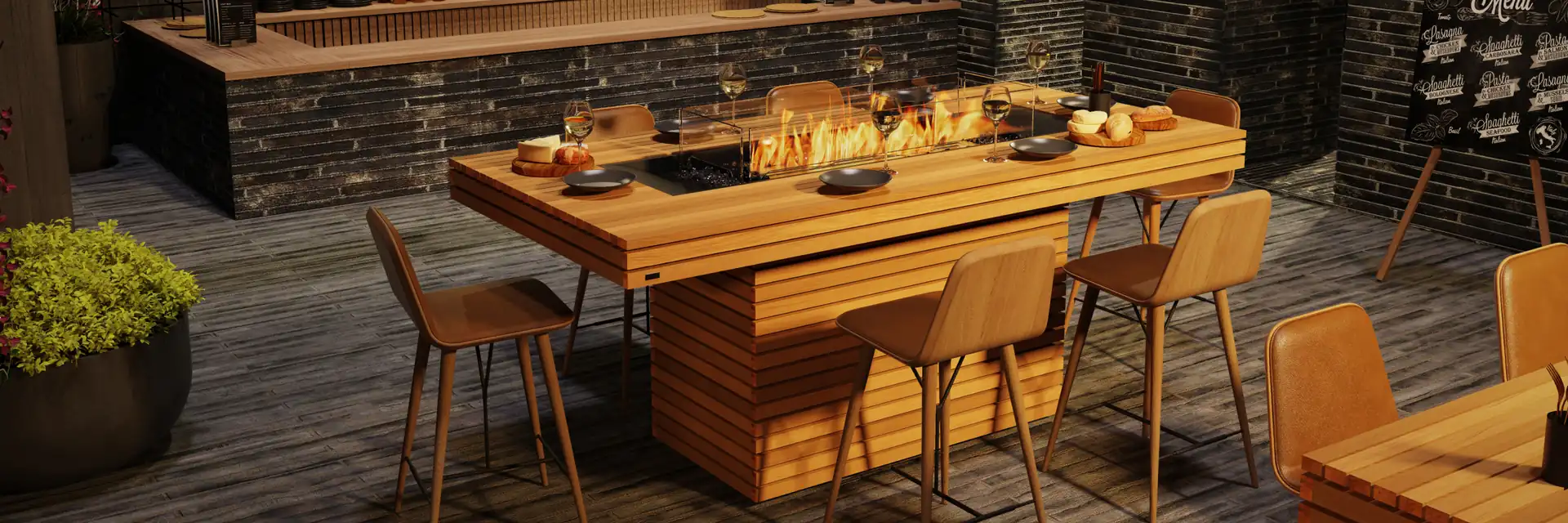 EcoSmart Gin 90 Bar fire table in teak with bar stools on a terrace, in front of a stone wall and a lit bar