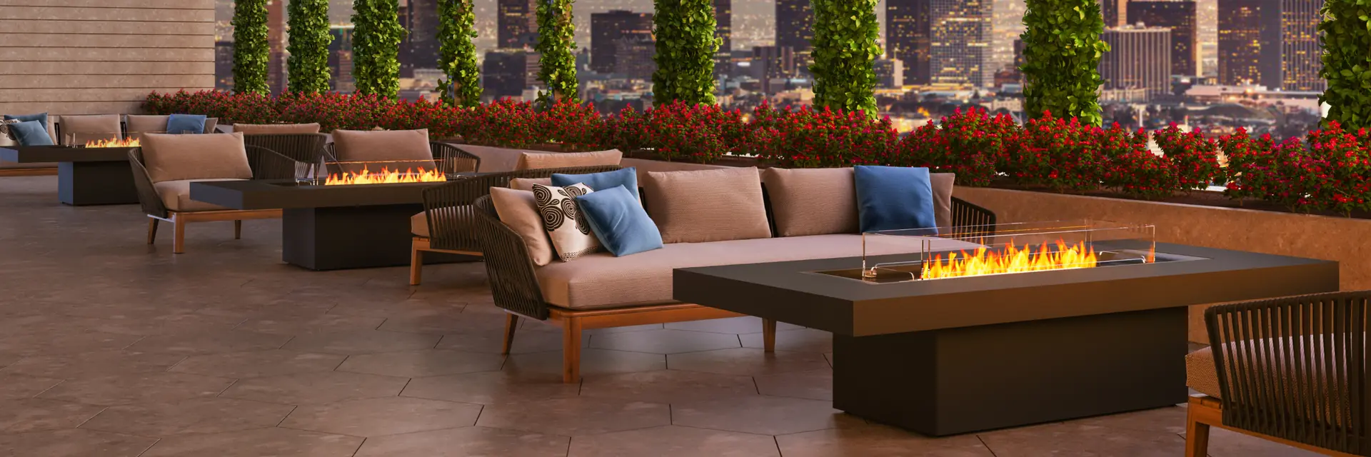 EcoSmart Gin 90 Chat fire table burning on a rooftop terrace with sofas and planted columns, with a city skyline at sunset