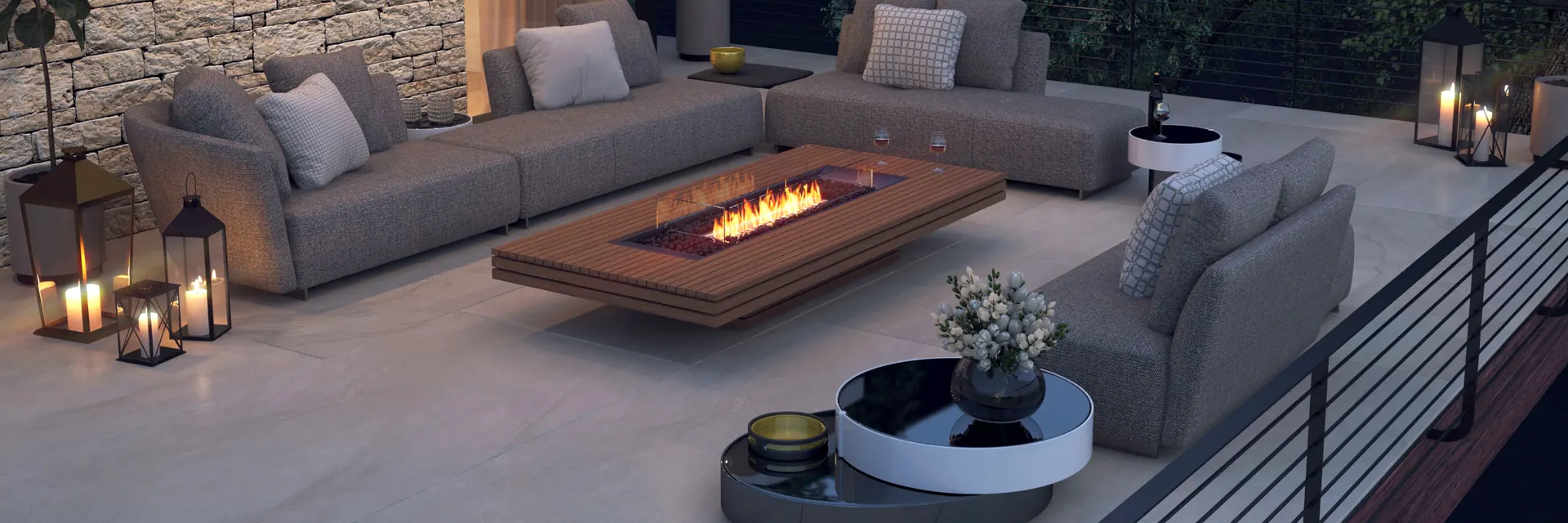 EcoSmart Gin 90 Low fire table in teak burning between gray sofas on a terrace at night, beside a stone wall