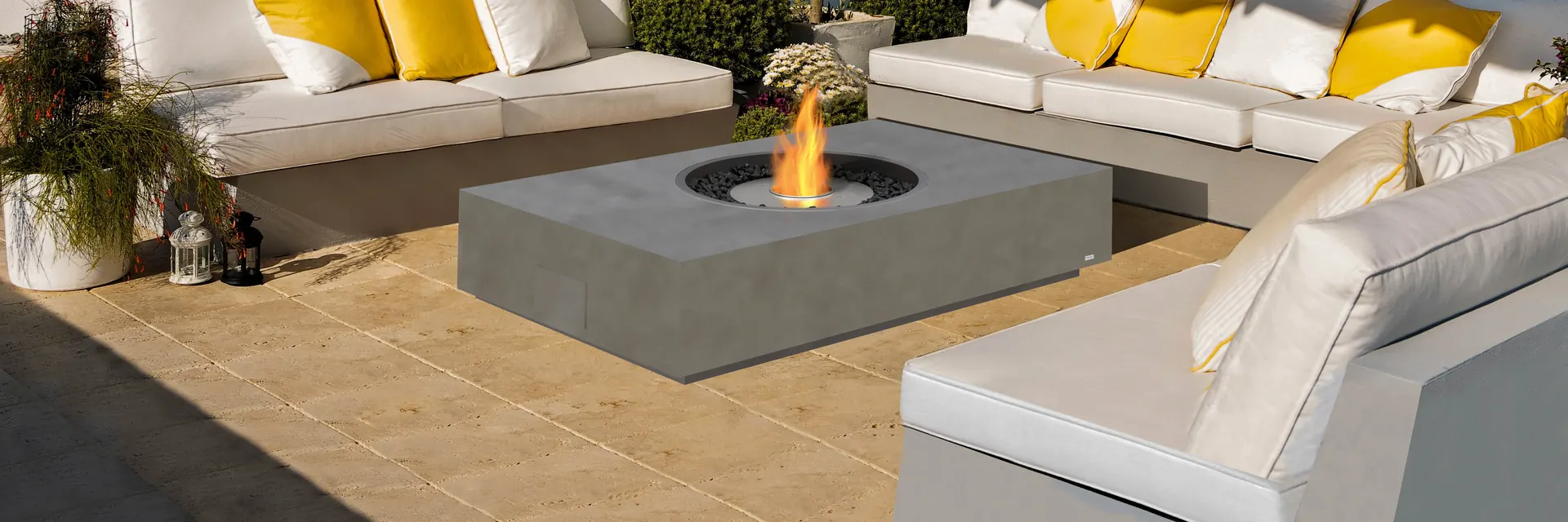 EcoSmart Martini 50 fire table burning between white sofas with yellow cushions on a stone terrace, below a gabion wall and a pergola