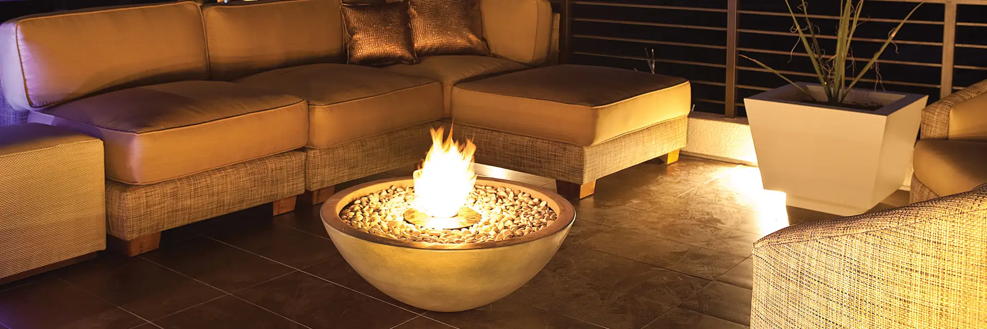 EcoSmart Mix 850 fire bowl burning beside a corner sofa on a rooftop terrace at night, with city lights below