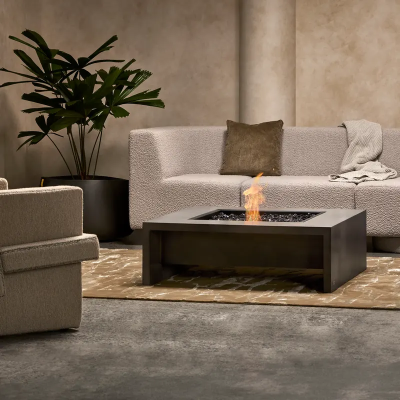 Square EcoSmart Mojito 40 fire table burning on a patterned rug in front of a pale sofa and a large plant