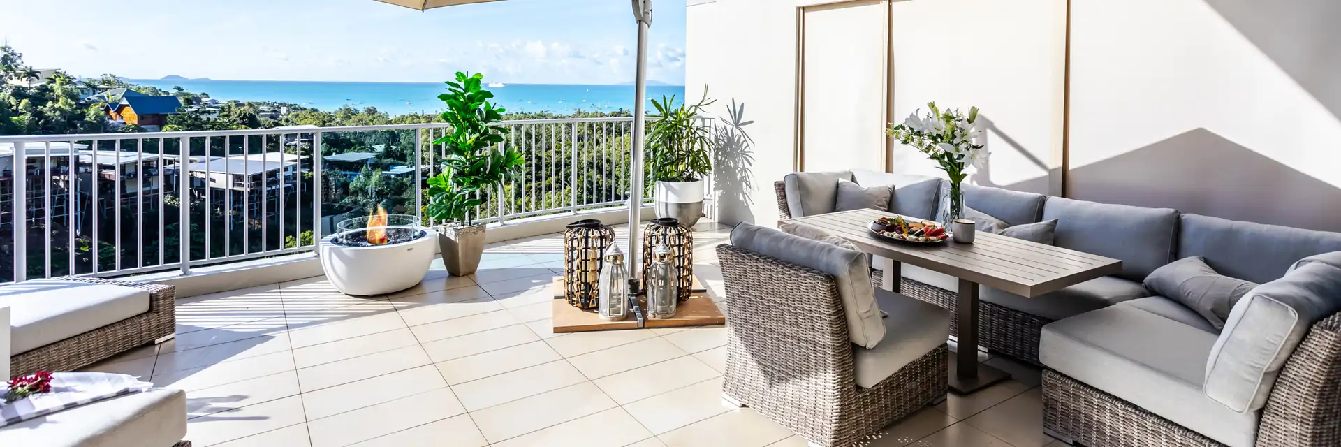 EcoSmart Pod 30 fire pit on a tiled terrace with wicker sofas under a parasol, overlooking the sea